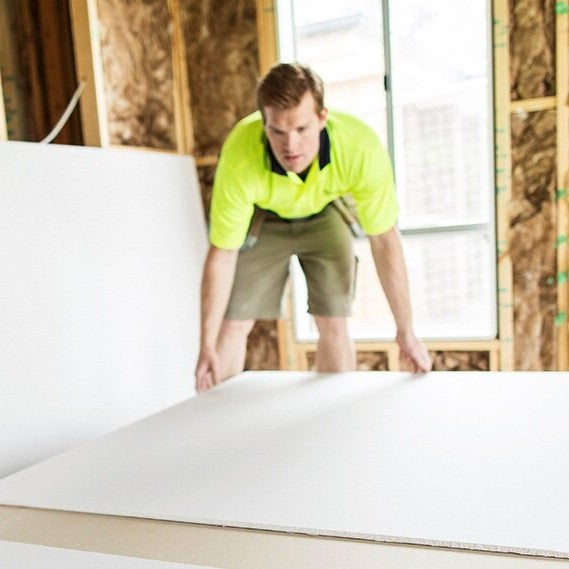 Man picking up sheet of plasterboard
