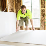 Man picking up sheet of plasterboard